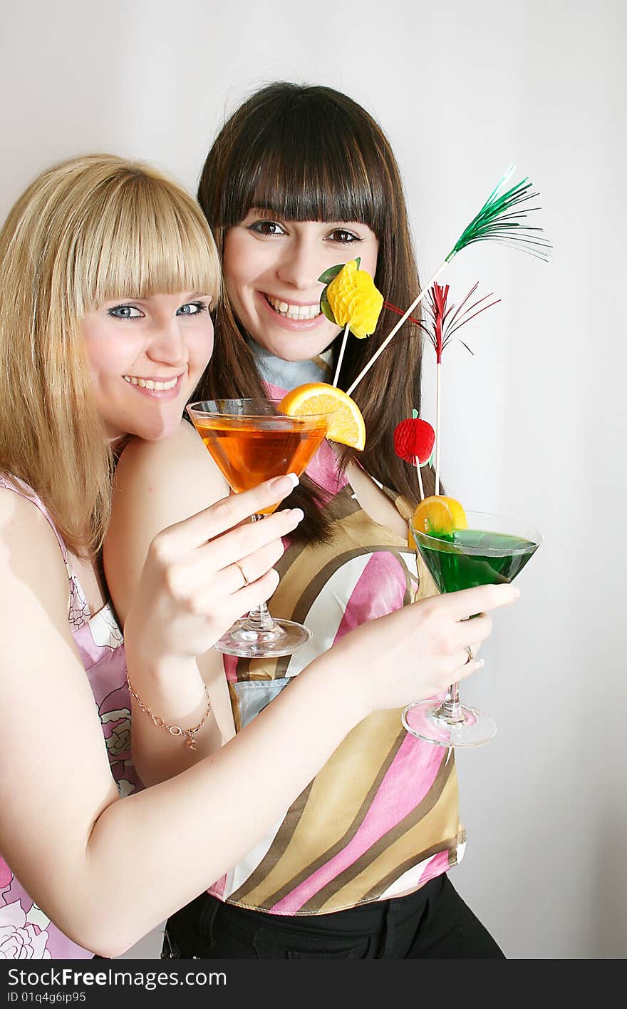 Two attractive young woman holding glass of cocktail in hand, smiling. Two attractive young woman holding glass of cocktail in hand, smiling.