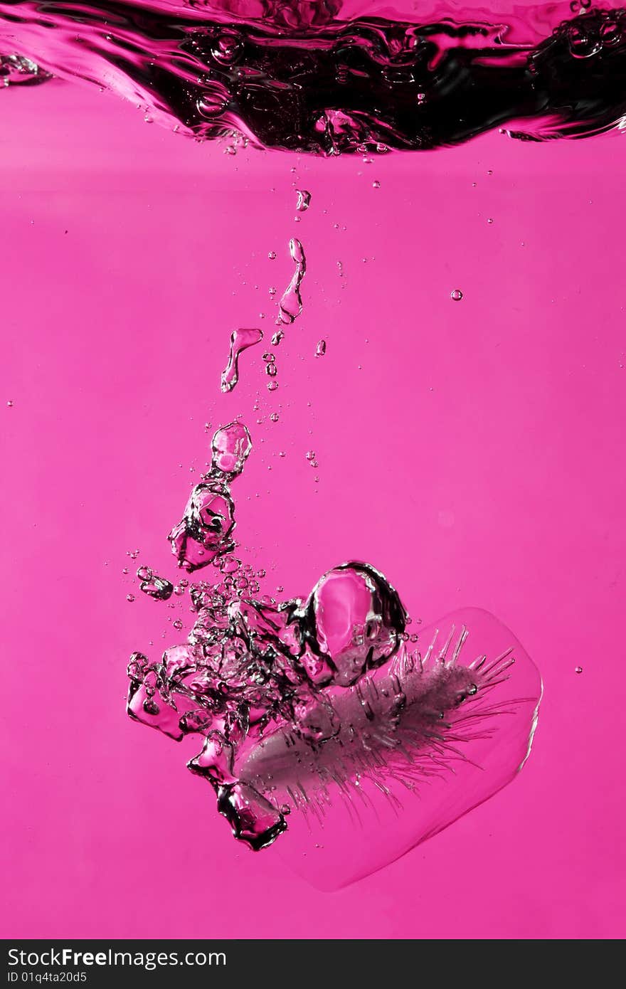 Ice with bubbles splashing underwater against pink background. Ice with bubbles splashing underwater against pink background