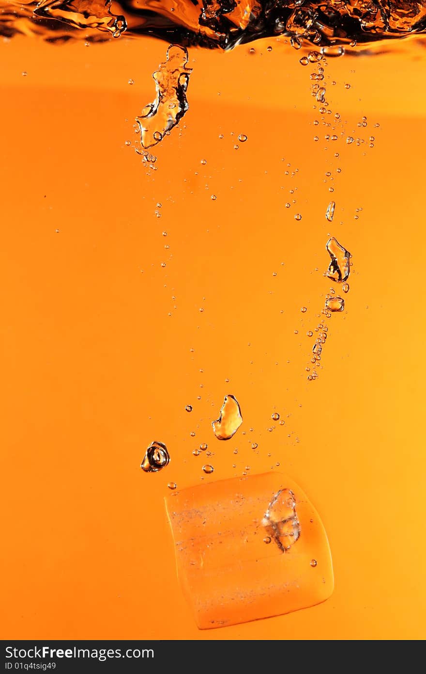 Ice with bubbles splashing underwater against orange background. Ice with bubbles splashing underwater against orange background