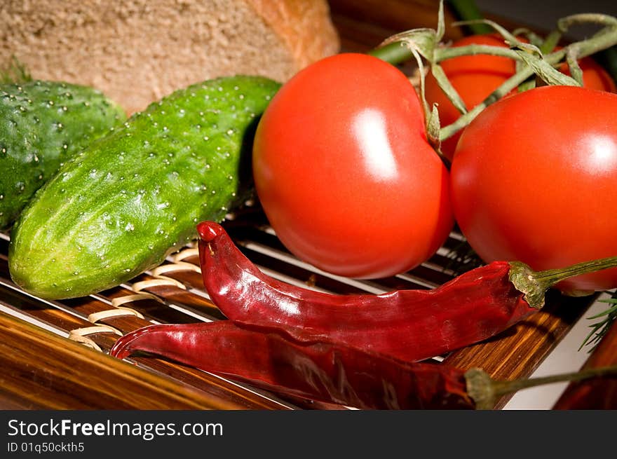 Three tomatoes, two cucumber and peppers with bread on wooden tray. Three tomatoes, two cucumber and peppers with bread on wooden tray