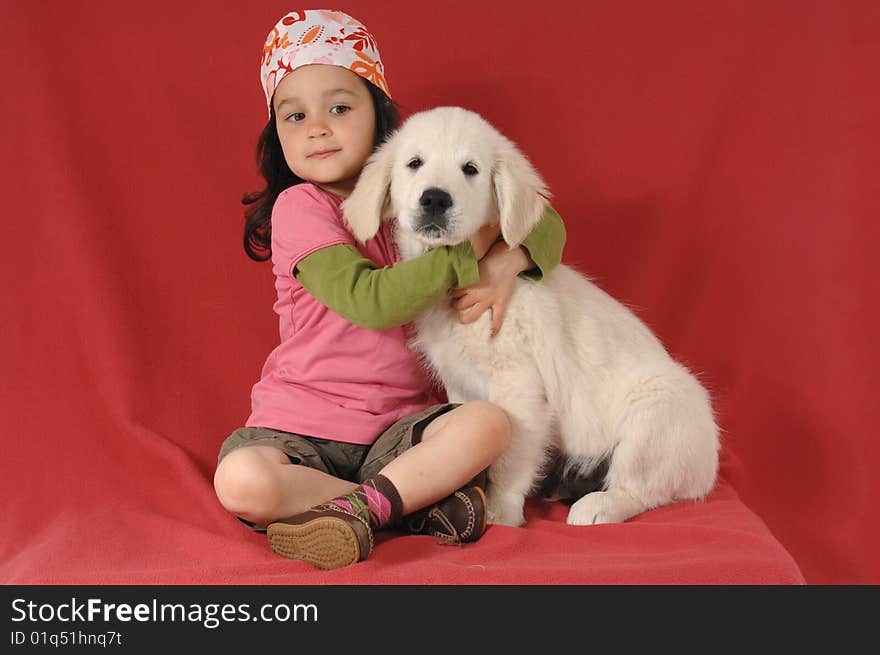 Little girl with a Golden retriever puppy on studio