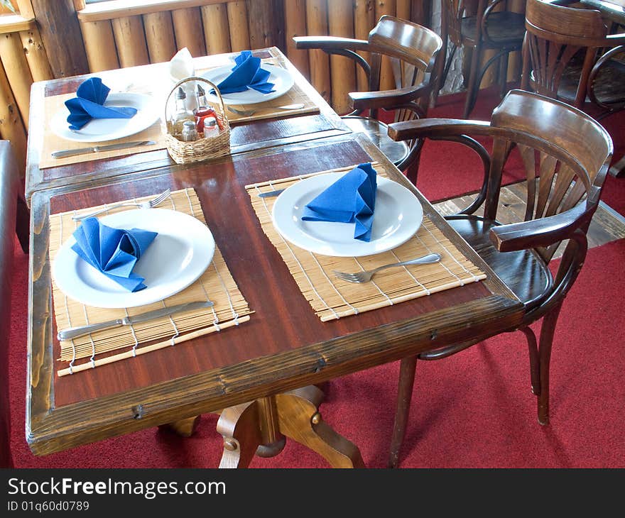 Plaits and silverware with blue napkin on table. Plaits and silverware with blue napkin on table