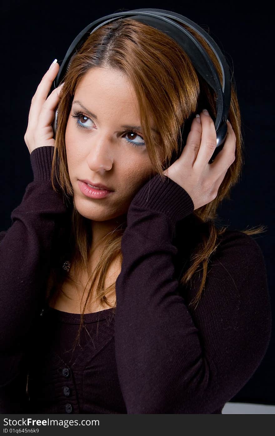 Portrait of young woman listening music through headphone