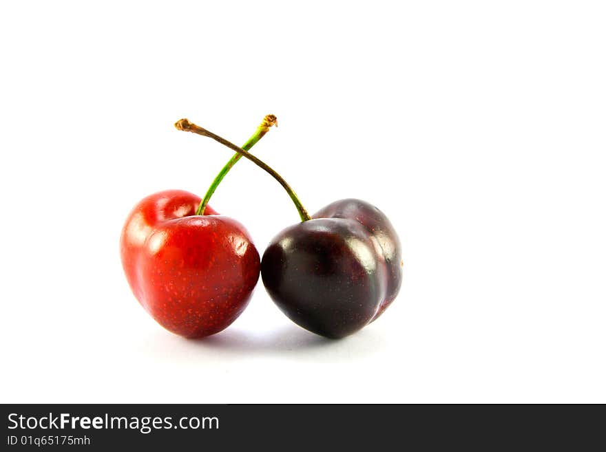 Two cherries one red one black on a white background with clipping path