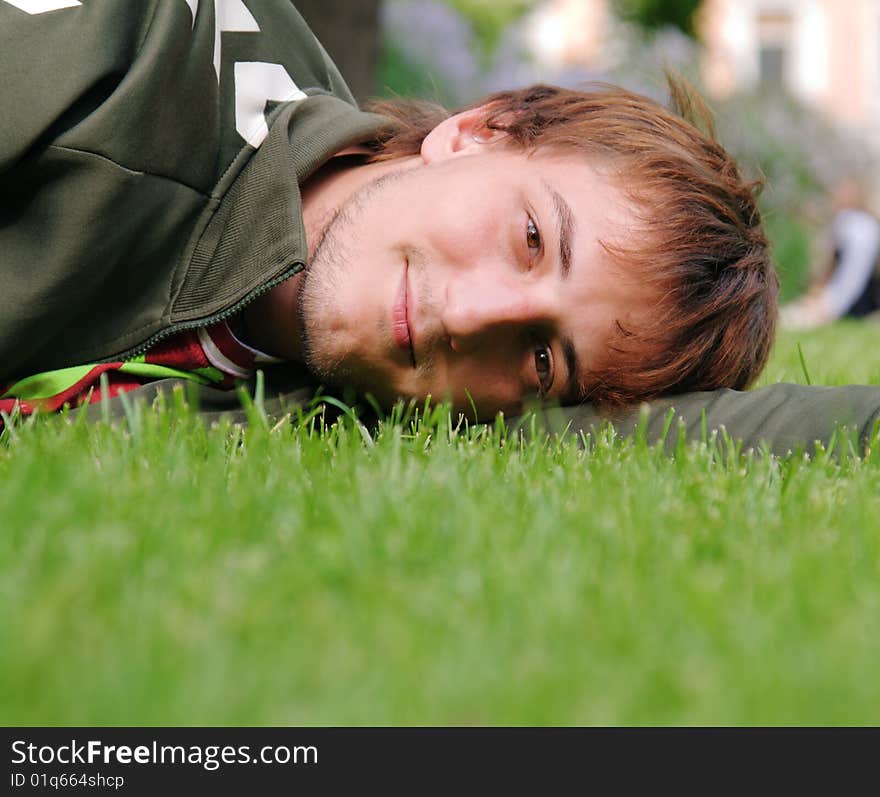 Young man lying on green grass