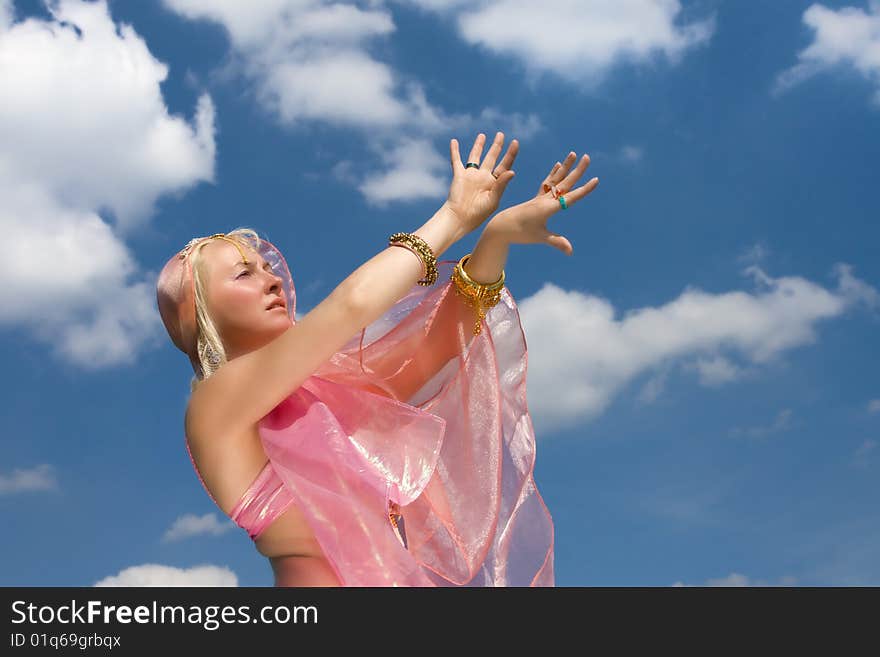 A woman in asian dress danccing and a blue sky