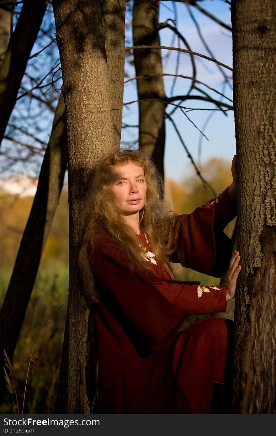 The blonde girl in medieval red dress in the autumn forest. The blonde girl in medieval red dress in the autumn forest