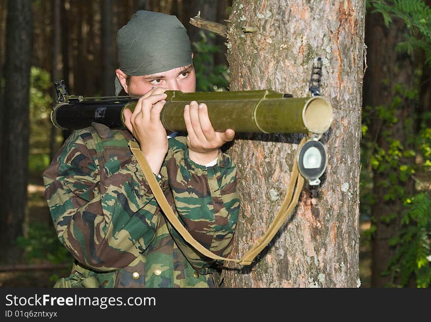 Man in a camouflage shoots from a grenade launcher