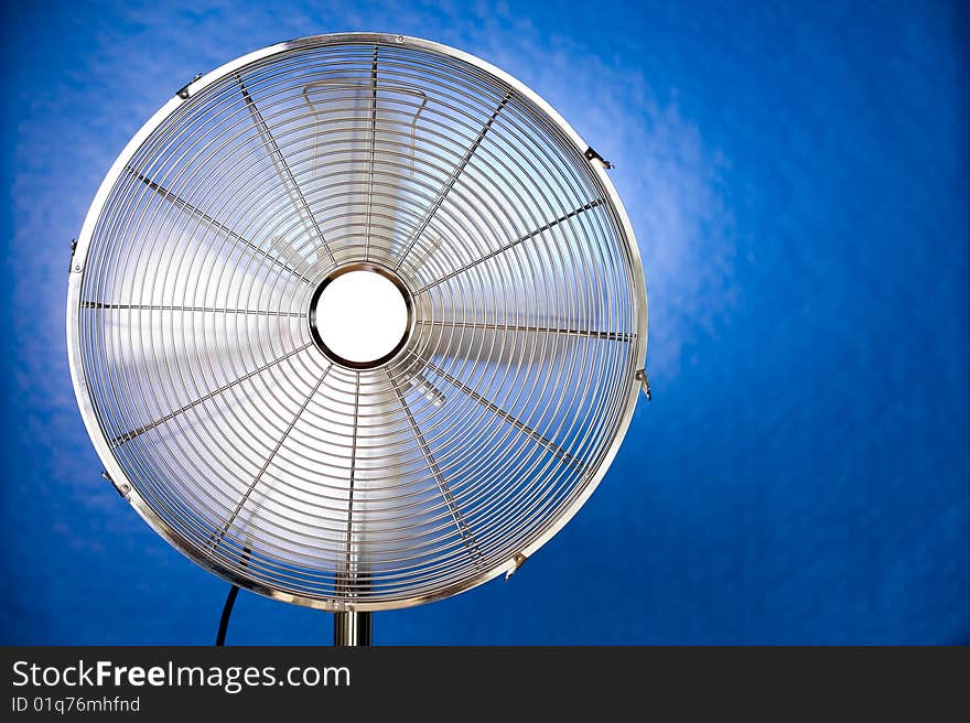 A working metal fan on a blue background