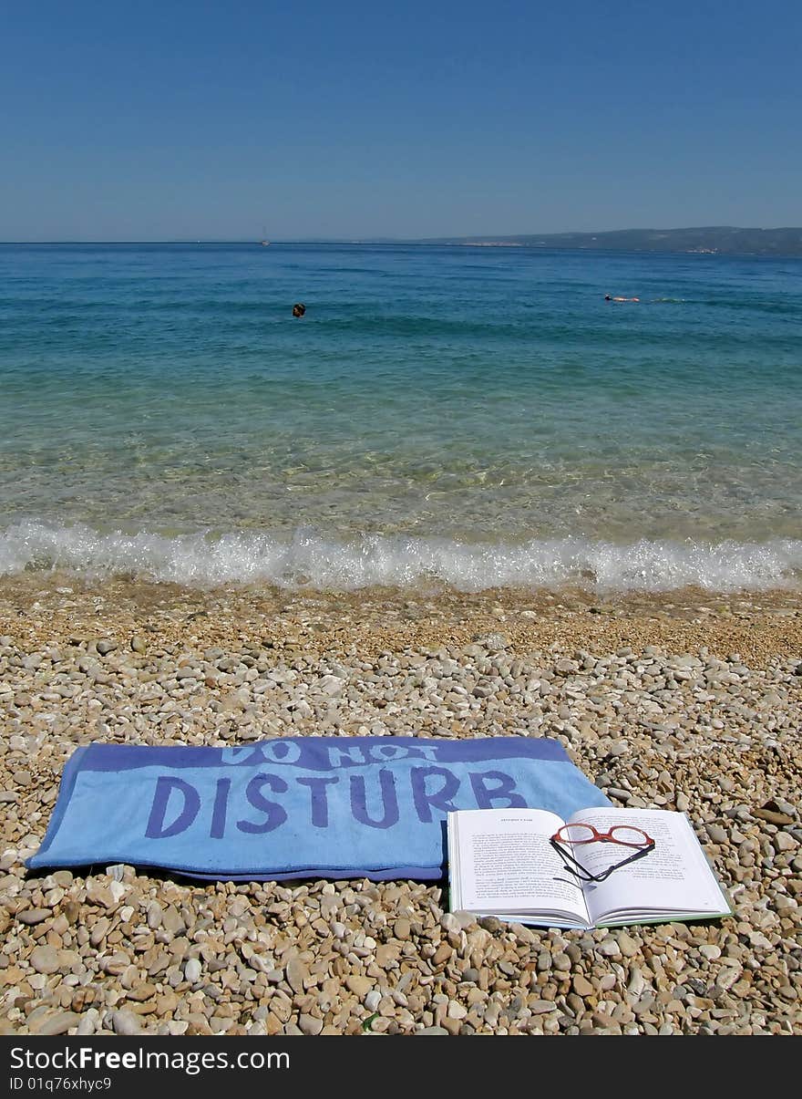 Wet towel do not disturb beach with blue-green sea. Wet towel do not disturb beach with blue-green sea