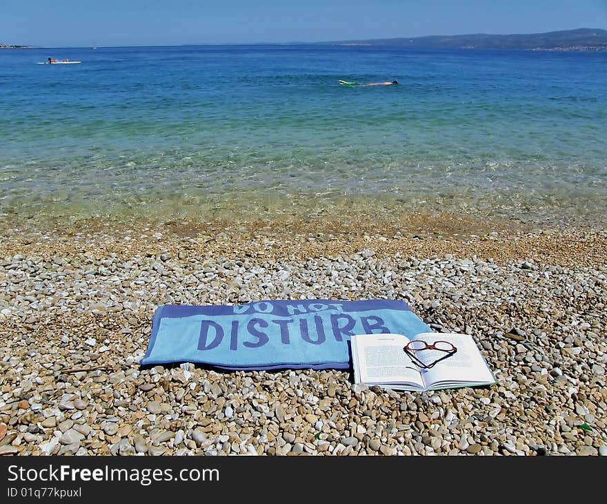 Towel do not disturb on beach with blue-green sea. Towel do not disturb on beach with blue-green sea