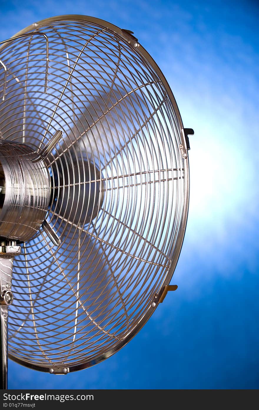 Backside of a working metal fan on a blue background. Backside of a working metal fan on a blue background