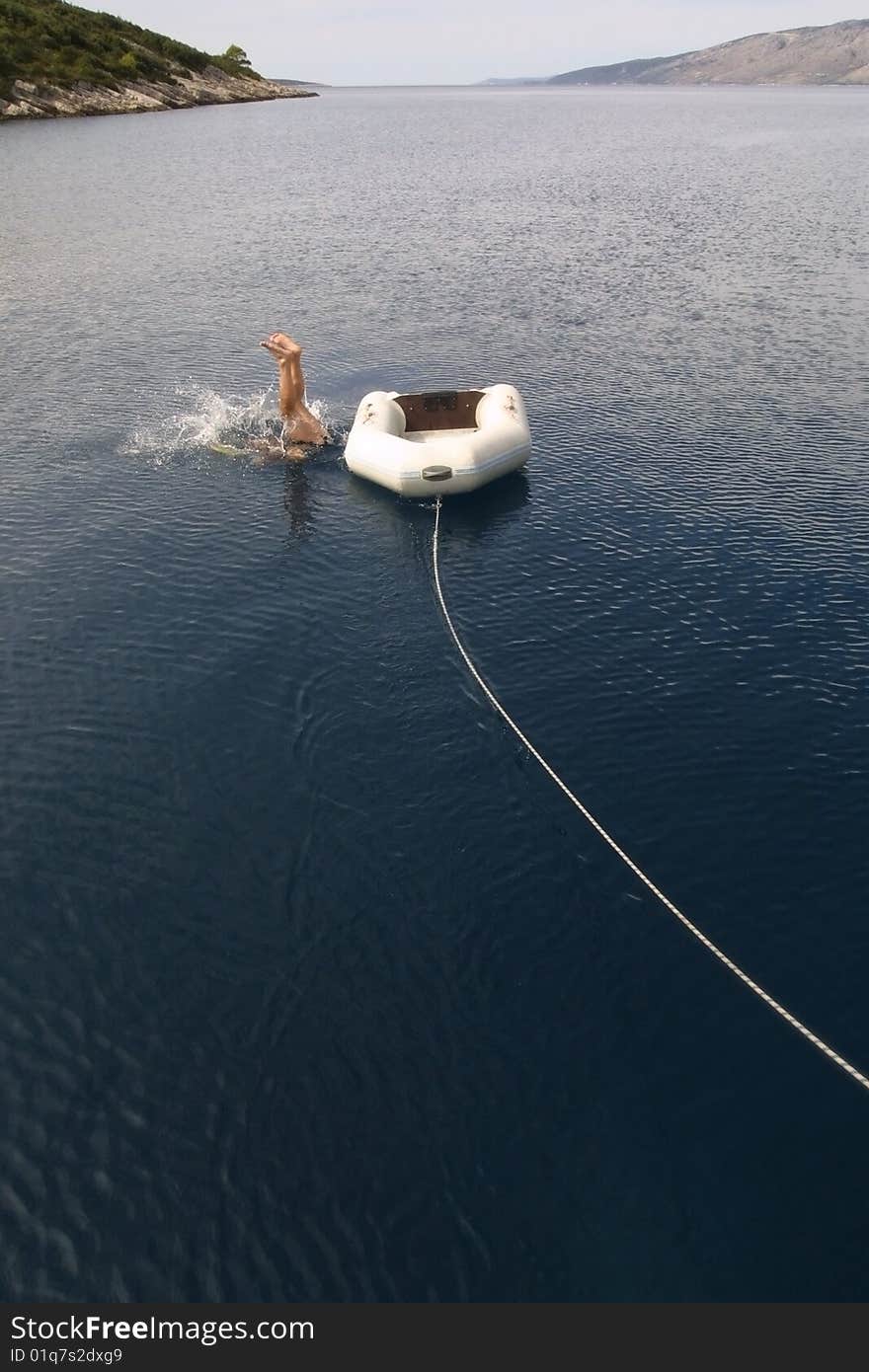 A man is jumping into sea from a small boat on a remote location into beautiful blue Mediterranean. A man is jumping into sea from a small boat on a remote location into beautiful blue Mediterranean