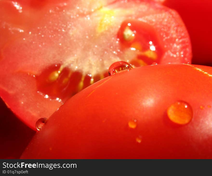 Halves of tomatoes with water drops one of which serve as spherical lens. Halves of tomatoes with water drops one of which serve as spherical lens