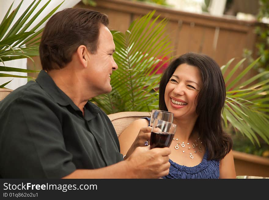 Attractive Hispanic and Caucasian Couple Drinking Wine Outside.