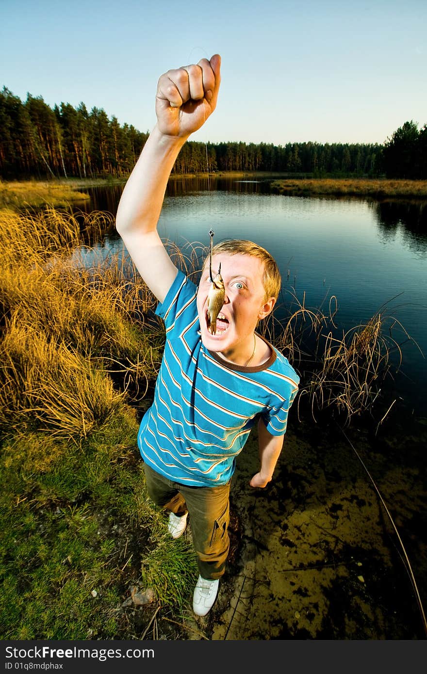 A cute guy showing off a crucian he has just caught. A cute guy showing off a crucian he has just caught