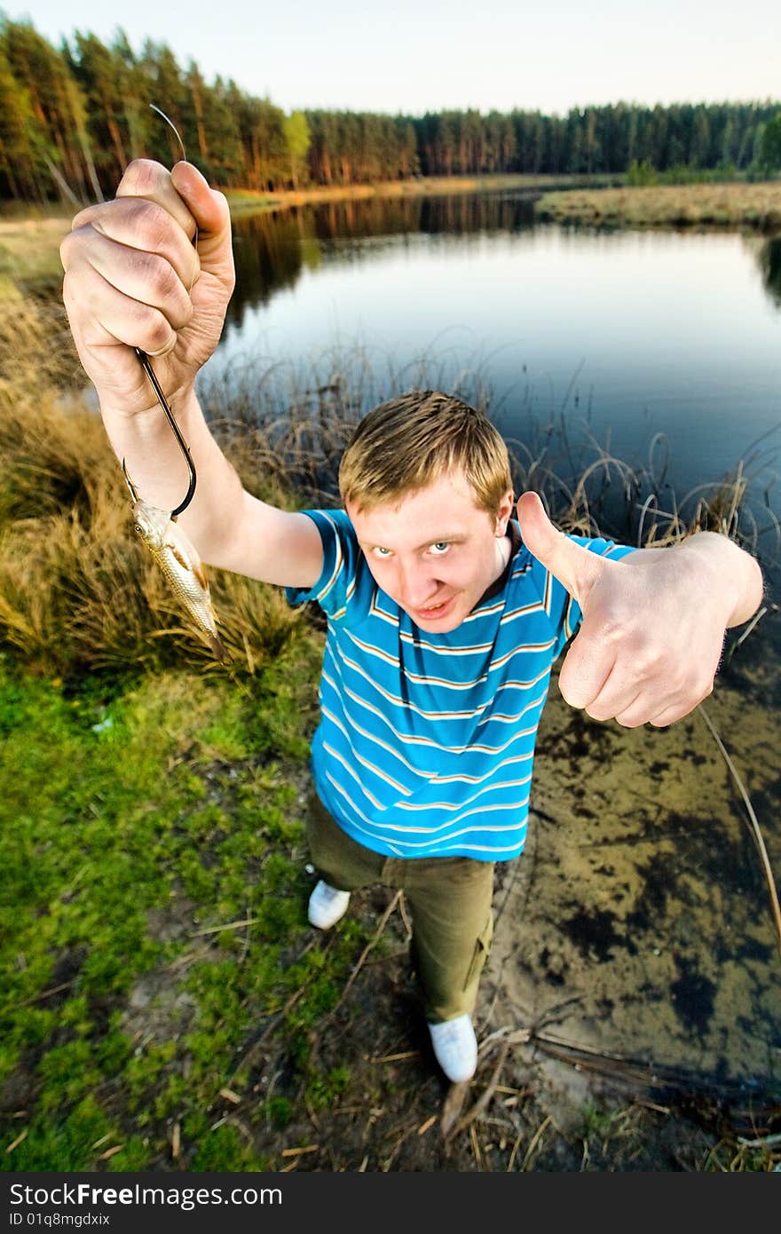 A cute guy showing off a crucian he has just caught. A cute guy showing off a crucian he has just caught