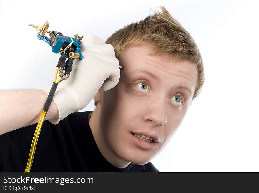 An image of a man with a tool for tatoo at his temple