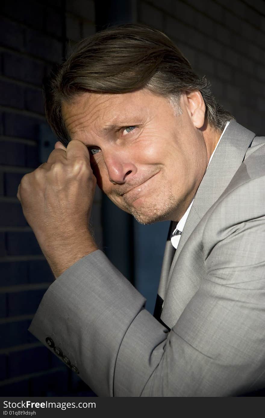 A colour portrait of a smart businessman looking depressed and emotional as he clenches his fist. A colour portrait of a smart businessman looking depressed and emotional as he clenches his fist.