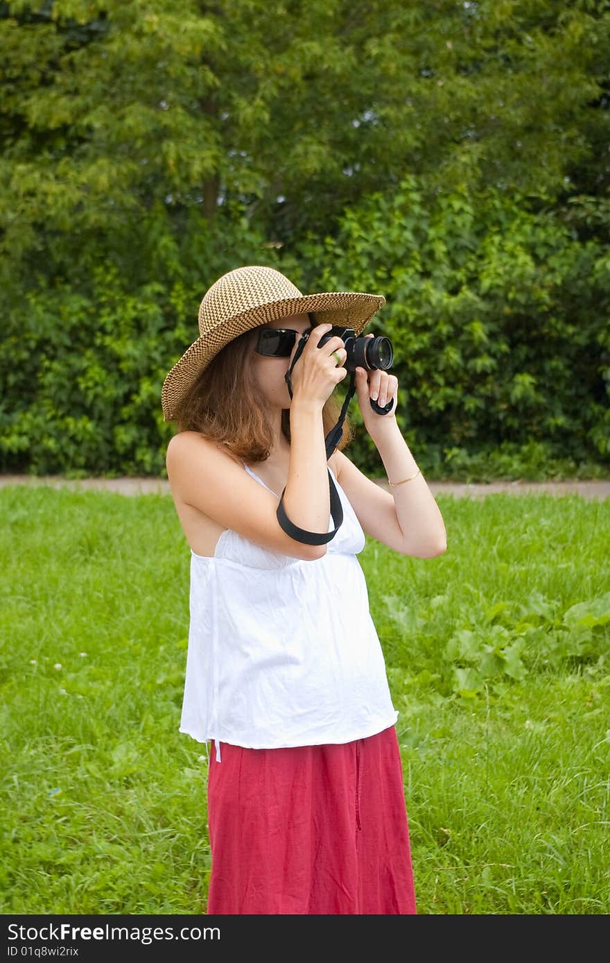 Portrait of a young girl in hat and sunglasses looking in digital camera. Portrait of a young girl in hat and sunglasses looking in digital camera