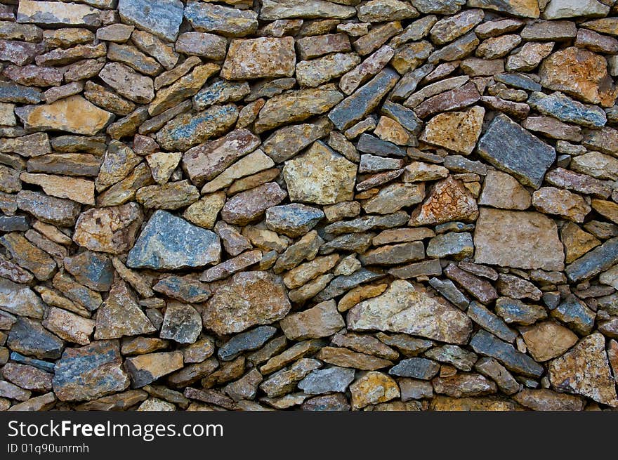 A mix of natural stone is loose stacked to form a wall. A mix of natural stone is loose stacked to form a wall