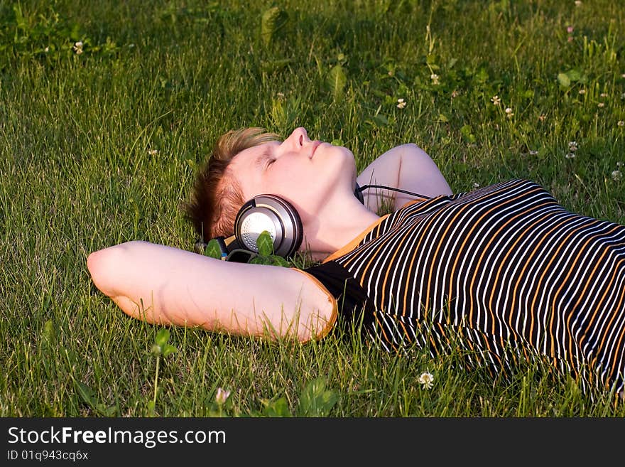 Teenager on a fresh green grass listening music. Teenager on a fresh green grass listening music