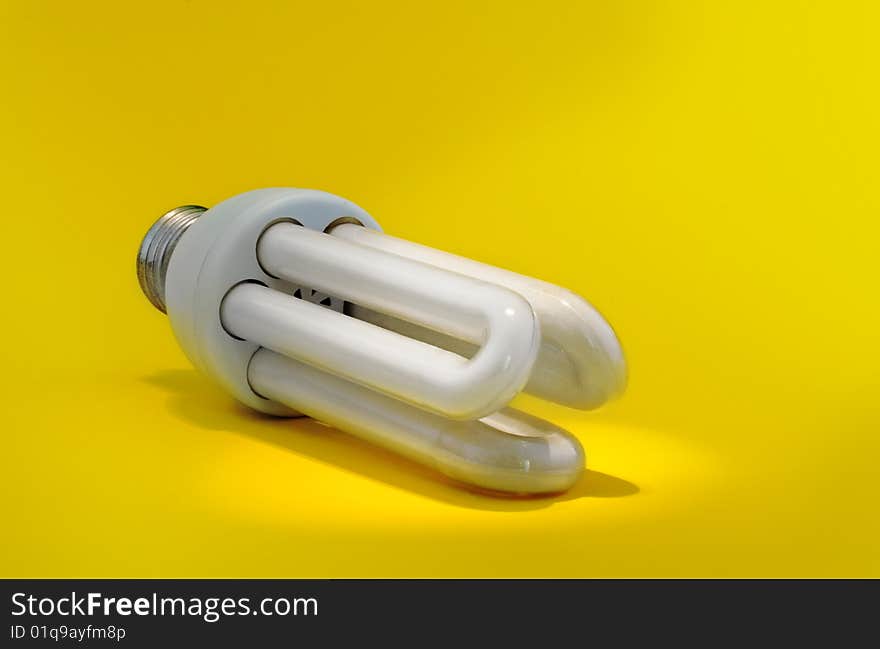 New energy: energy saving bulb under light spot on yellow