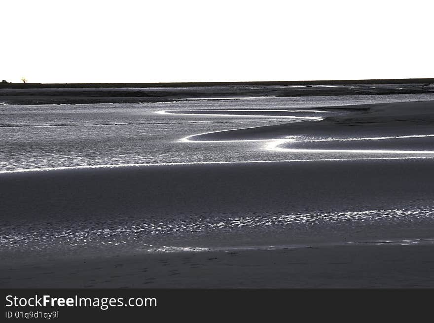 Beach after the sunset, ocean surface with shining ripple