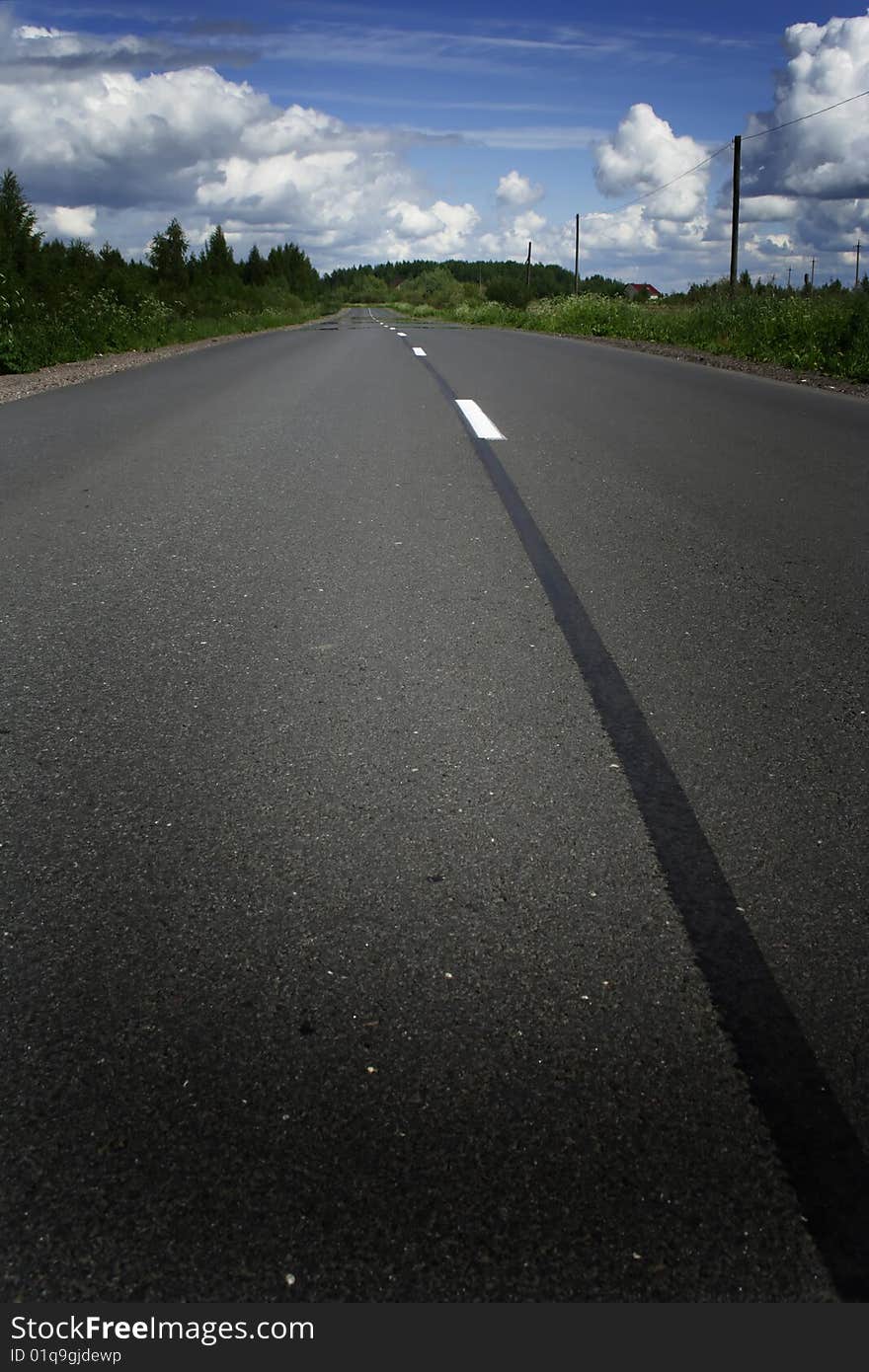 Green grass, the blue sky and white clouds and road