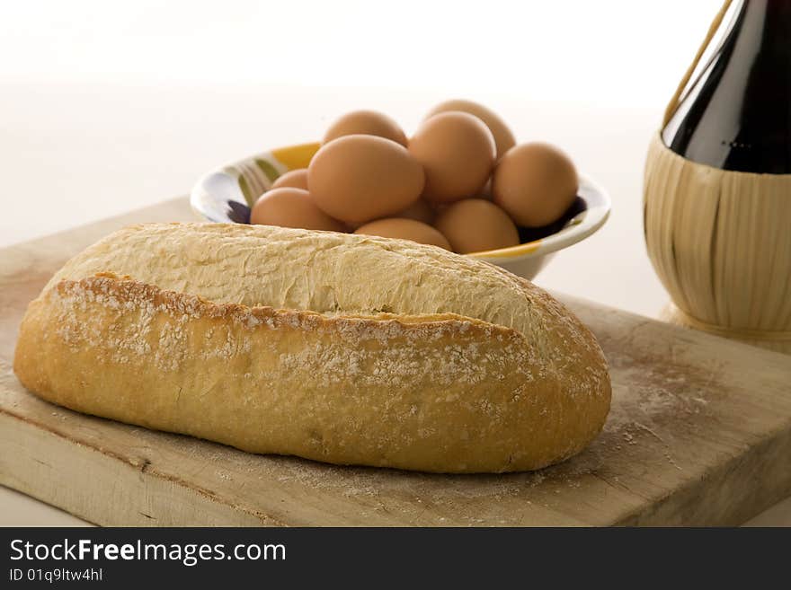 Italian artisan bread on cutting board with eggs and wine. Italian artisan bread on cutting board with eggs and wine.