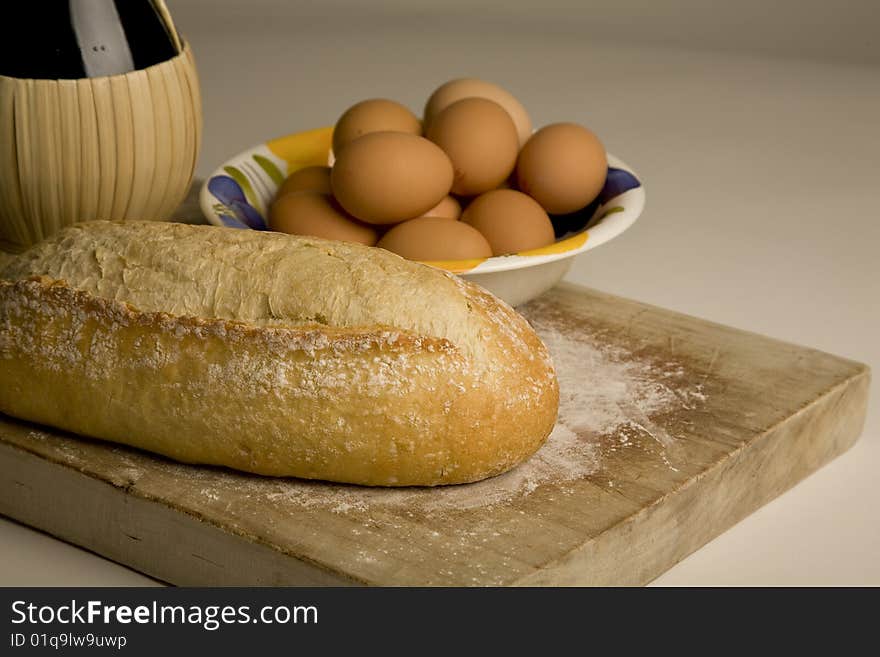 Italian artisan bread on cutting board with eggs and wine. Italian artisan bread on cutting board with eggs and wine.