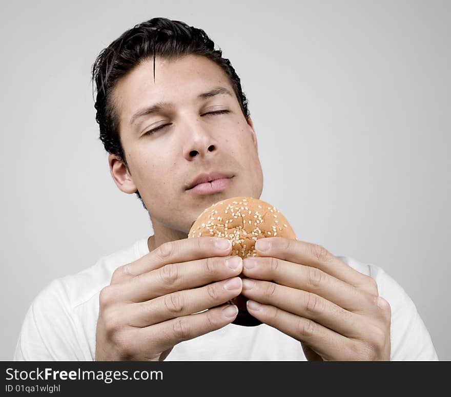 Young man smells a tasty big burger. Young man smells a tasty big burger