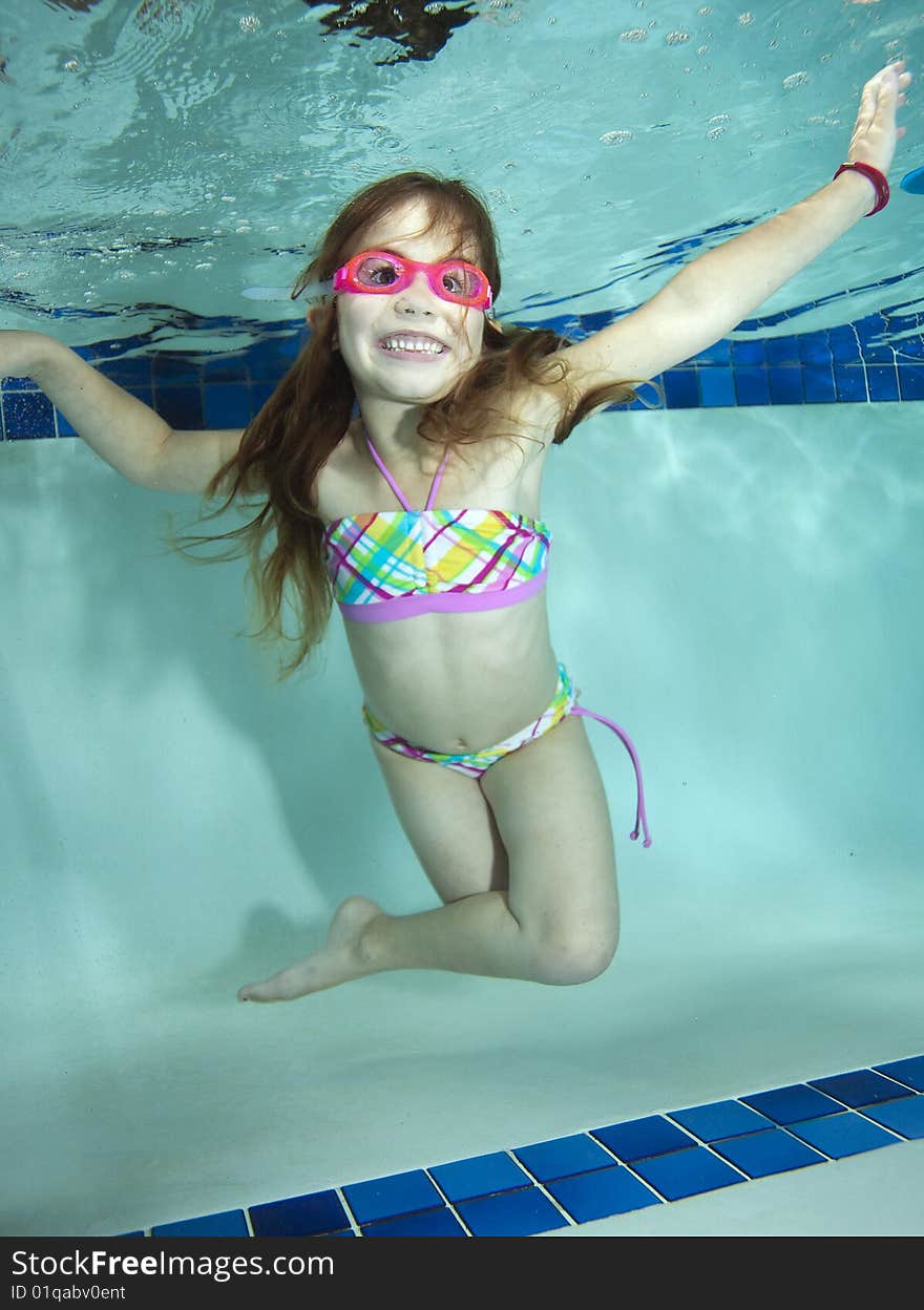 Happy little girl underwater in pool