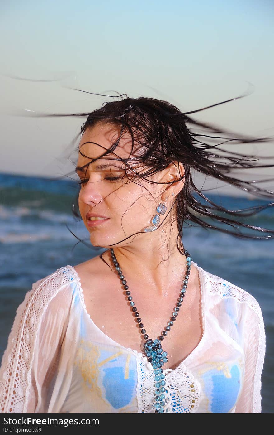 Portrait of young woman waving wet hair on the beach