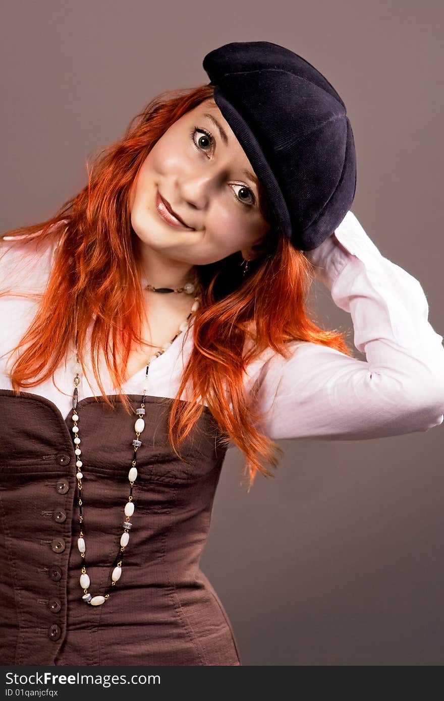 Red haired young woman in hat smiling isolated over grey