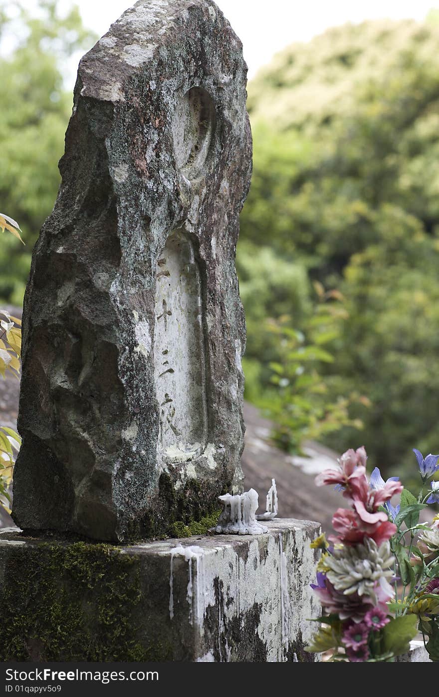 A Buddhist headstone memorial marked with the year of the person's death and a candle partially burned in front. This photo is represented on my website () at the following link: Please visit and provide feedback on this and related images.