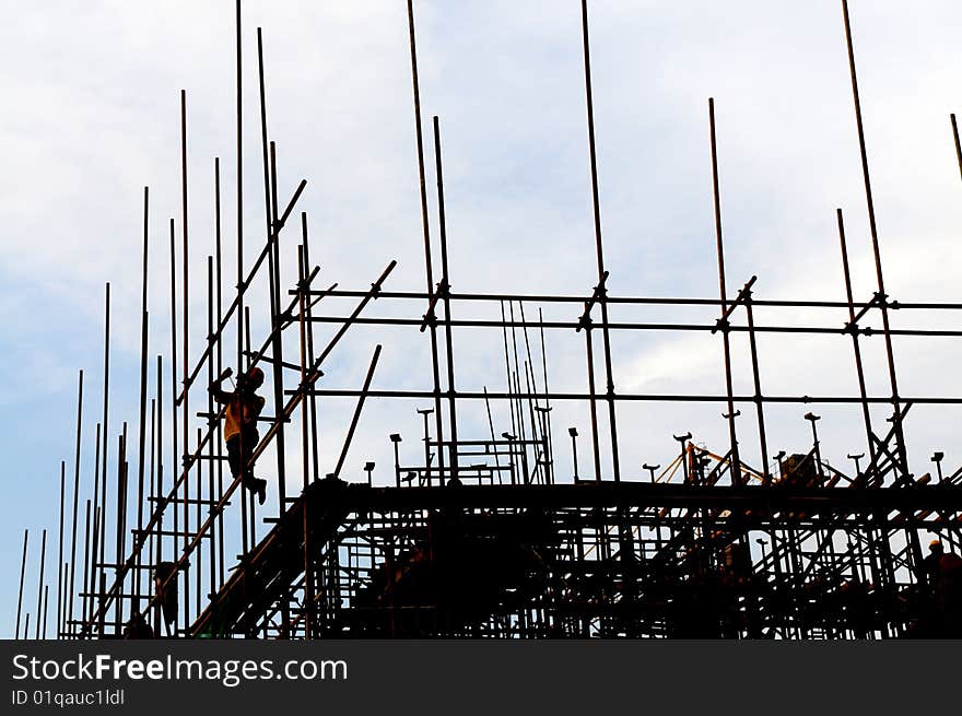 The workers on scaffolds under the blue sky.