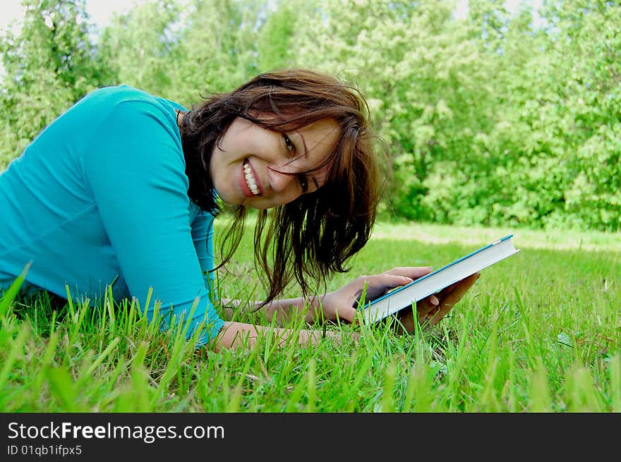 Young beautiful woman lays on green field