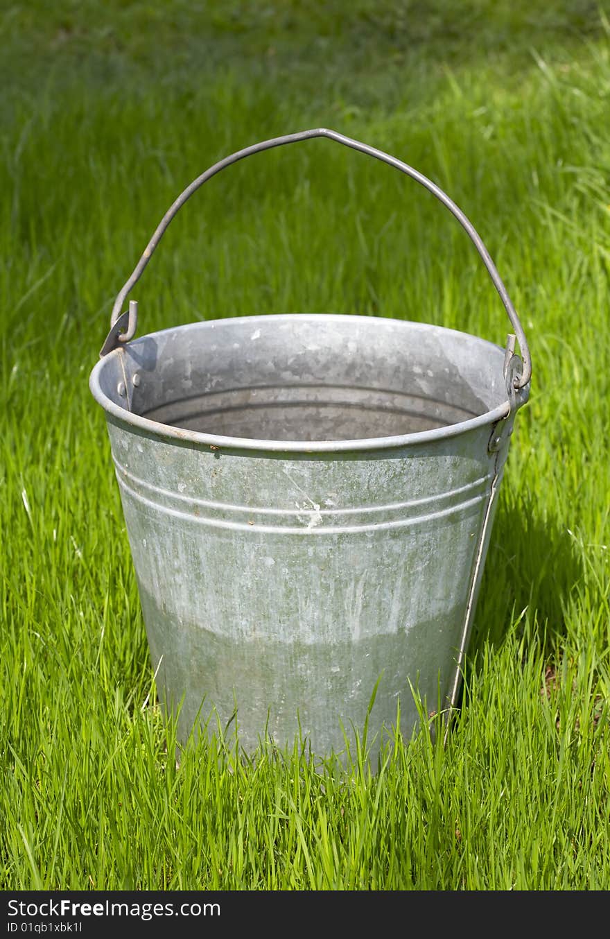 Old bucket stands on green grass. Old bucket stands on green grass