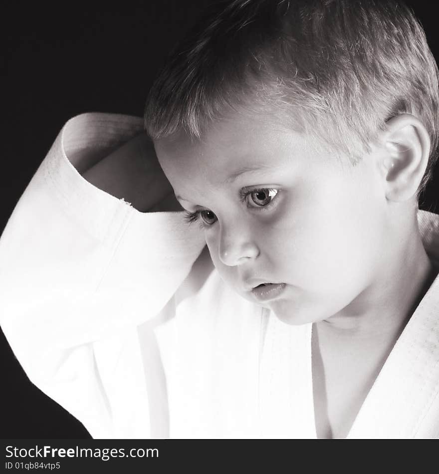 Young boy wearing his karate uniform on a black background. Young boy wearing his karate uniform on a black background