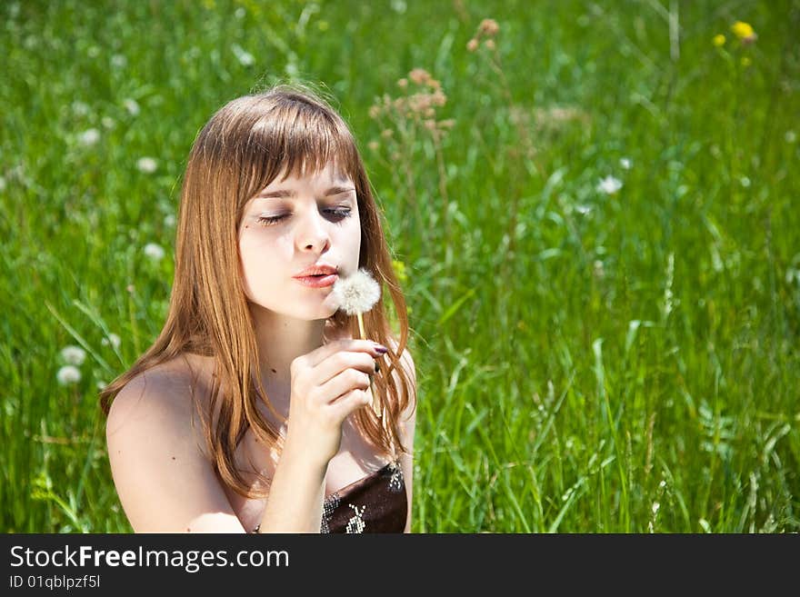 Young beautiful girl blowing on � dandelion. Young beautiful girl blowing on � dandelion