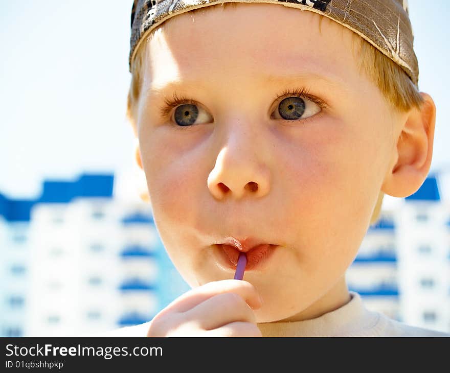 The little boy with a sweet in a hand costs in the street. The little boy with a sweet in a hand costs in the street