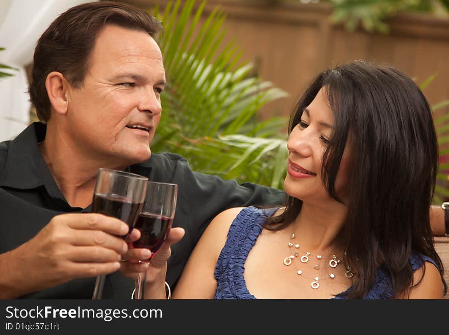 Attractive Hispanic and Caucasian Couple Drinking Wine Outside.