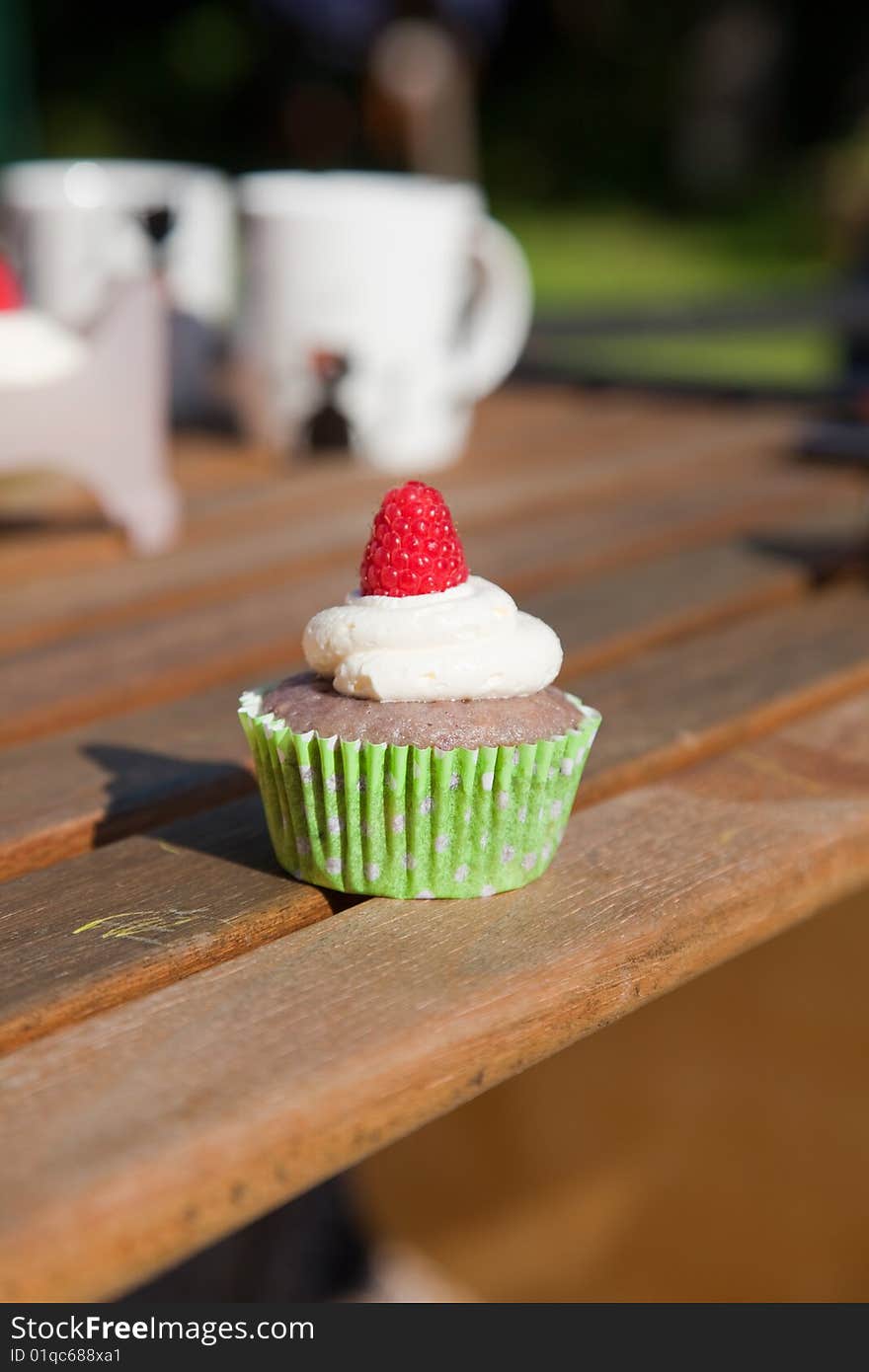 Raspberry cream cupcake on picnnic table. Raspberry cream cupcake on picnnic table.