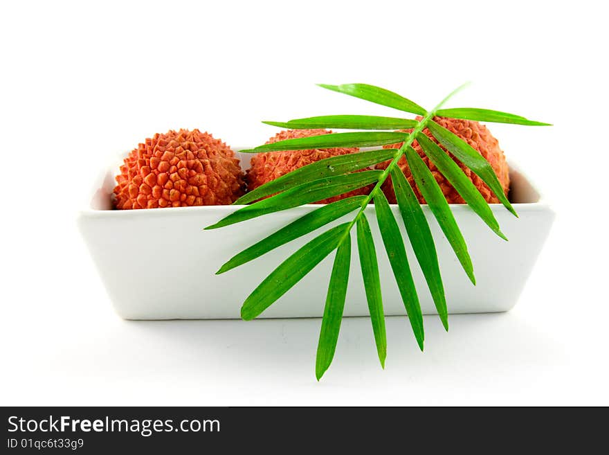 Three lychee and a green leaf in a dish with clipping on a white background. Three lychee and a green leaf in a dish with clipping on a white background