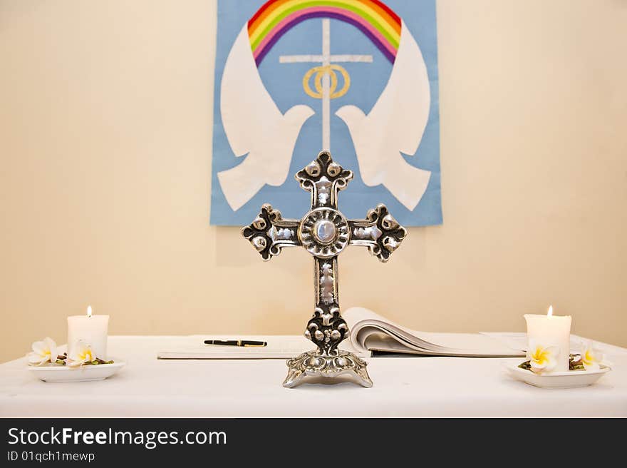 A Christian church pulpit with a cross and two candles.  The doves of peace is on a sign on the wall.