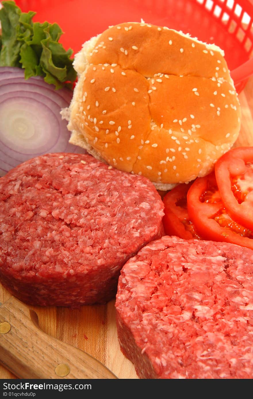 Picnic ingredients for hamburgers including patties, buns, lettuce, tomatoes and onions