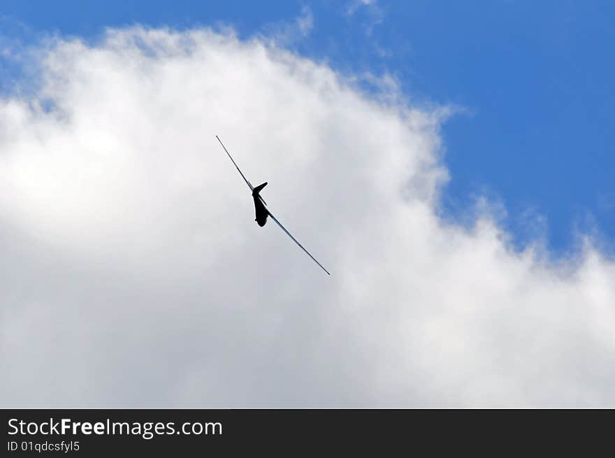 A sailplane against blue sky with white summer clouds