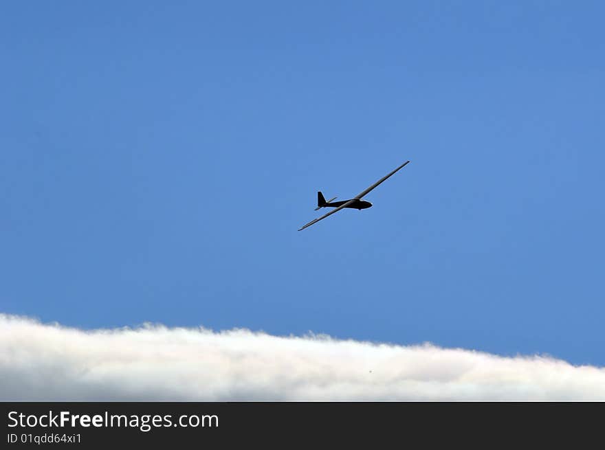 A sailplane against blue sky with white summer clouds