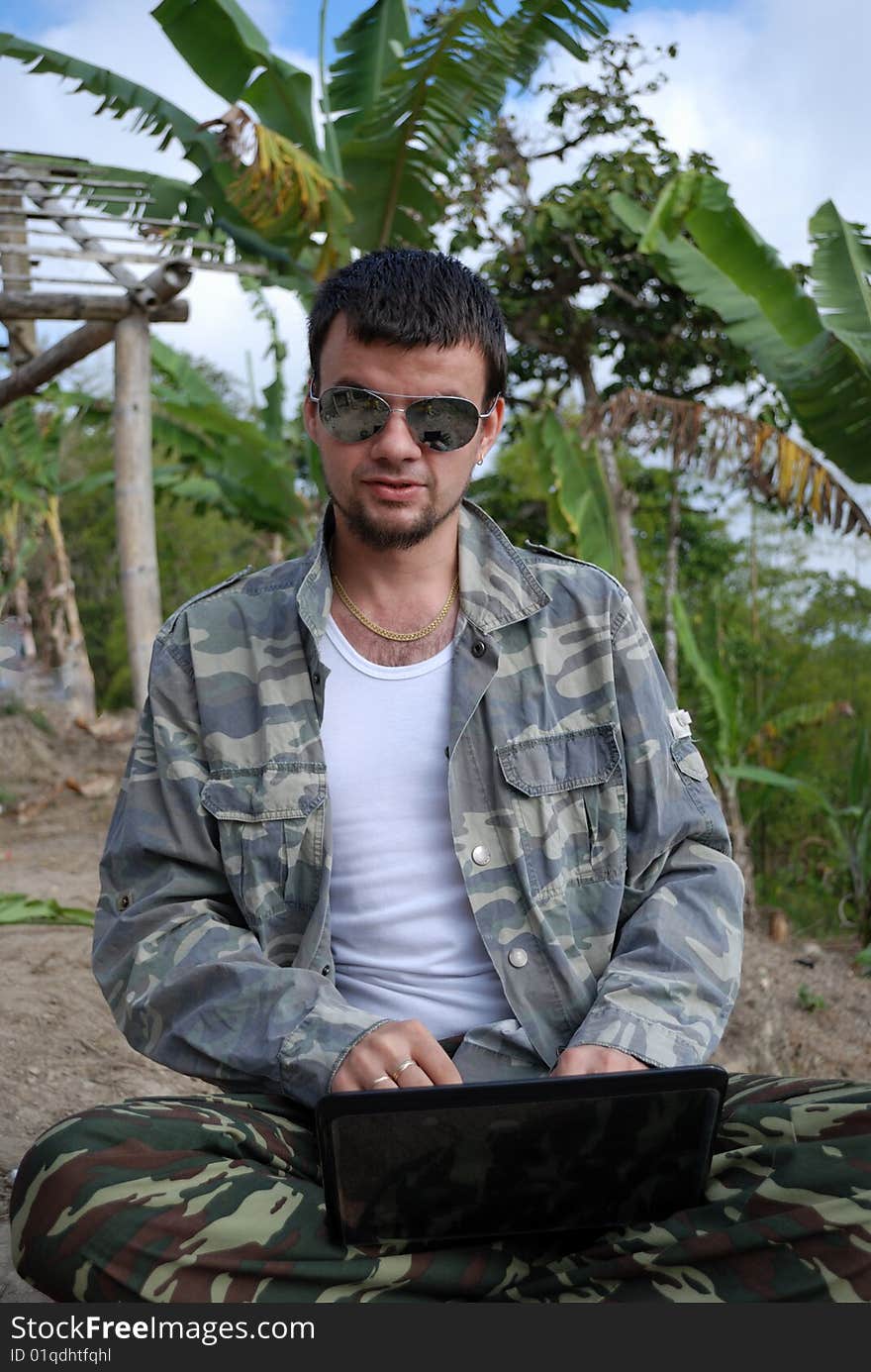 The young man with the computer and its new workplace in jungle